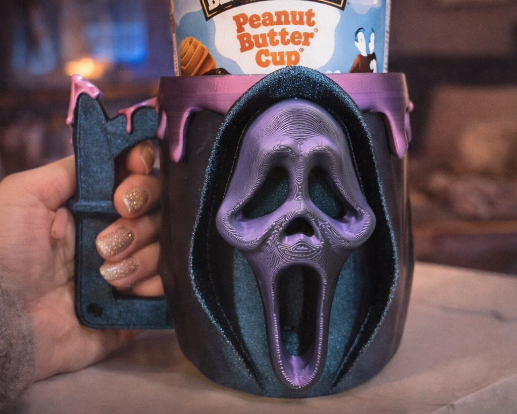 Ben & Jerry's Peanut Butter Cup ice cream in a 3D printed mug with a scream design, held by a hand.